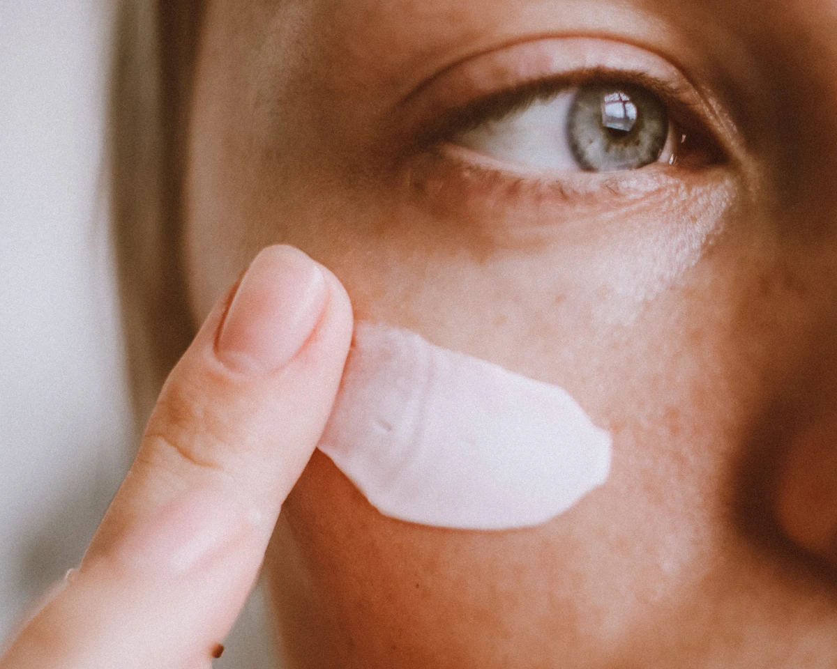 A woman applying cream under her eye